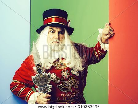 Frown Senior Man Beefeater Yeomen Warder Or Male Royal Guard Bodyguard In Red Uniform With Spear On 