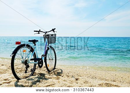 Feminine Bicycle Of Comfort Class With Empty Basket On The Sandy Beach Of Mediterranean Sea. Blue Cr