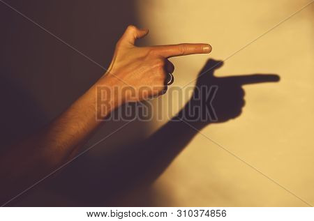 Human Hand Indicates The Direction Pointing With Index Finger, Gesture Shadow On Wall, Copy Space