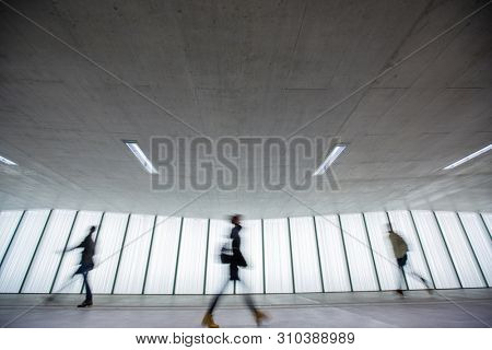 Motion blurred people - figures in an underpassage getting to their workplace in the morning. Busy city business life.