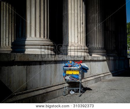 Munich, Bavaria, Germany - May 18, 2019. Homeless Shopping Cart At Königsplatz On A Spring Day With 