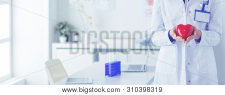 A doctor with stethoscope examining red heart, isolated on white background