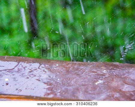 Rain Photographed From Opened Window, Close Up View. Raindrops On Brown Ledge. Selective Soft Focus.