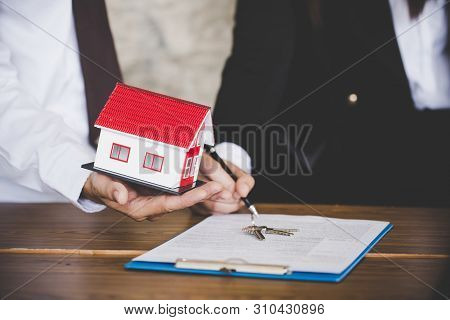 Estate Agent Giving House Keys To Female And Sign Agreement In Office