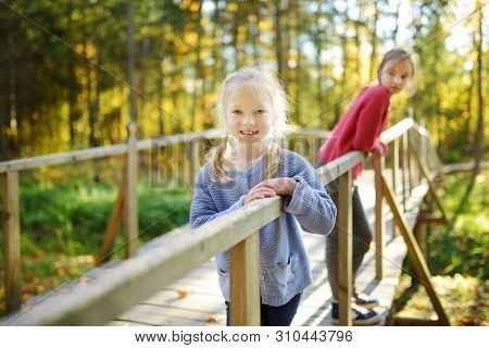Two Cute Young Sisters Having Fun During Forest Hike On Beautiful Summer Day. Children Exploring Nat