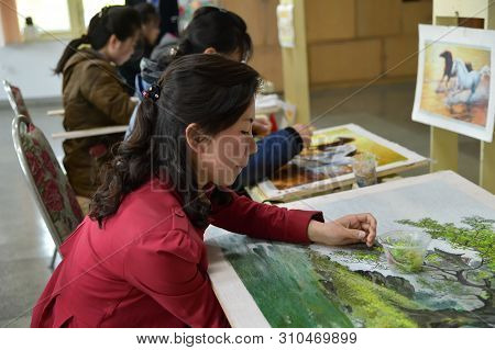 Pyongyang, North Korea - April 29, 2019: Girls Factory Workers With Needle And Silk Thread Over Canv
