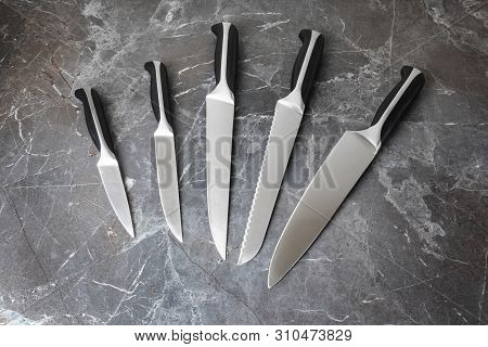 A Set Of Knives - Cook, Universal, For Bread, For Cutting And For Cleaning. Knives Lie On A Dark Gra