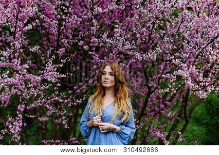 Beautiful Smilling Redhead Woman In Spring Time Blossom Cherrytrees Garden. Perfect Time For A Walk.