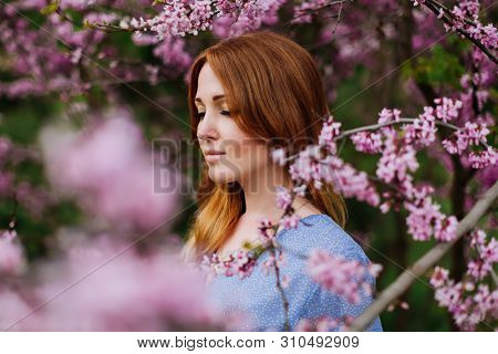 Beautiful Smilling Redhead Woman In Spring Time Blossom Cherrytrees Garden.