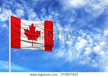 National Flag Of Canada On A Flagpole In Front Of Blue Sky