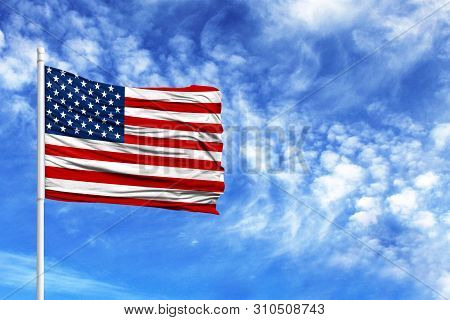 National Flag Of America On A Flagpole In Front Of Blue Sky