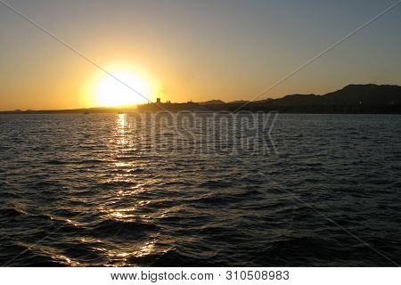 Red Sea Coast In Sharm El-sheikh, Egypt, Sinai, Red Setting Sun Over The Sea And The Silhouette Of T