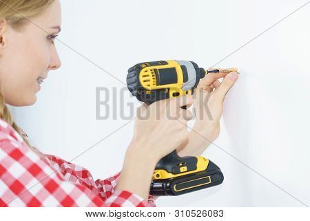 Woman Drilling In Wall