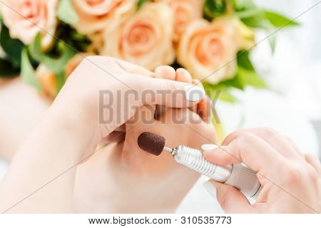 Podiatrist in podiatry session working of feet of client with machine