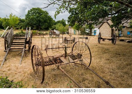 Old Carriages And Tools Standing On A Dry Meadow In Saint Lyphard