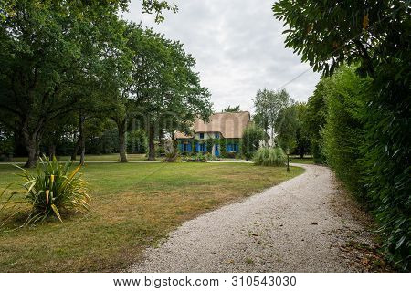 Small Road Leading To An Old House With A Thatched Roof