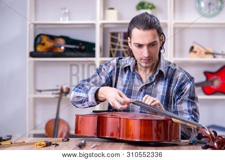 Young handsome repairman repairing cello