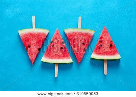 Fresh watermelon slices on sticks (seen from above).
