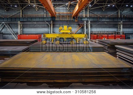 Overhead Crane With Magnetic Grippers Lifting Steel Sheets.