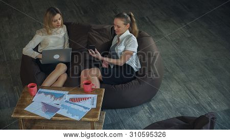 Two Beautiful Business Woman In Skirts Resting On The Couch, Holding A Laptop Girl, The Other Girl T