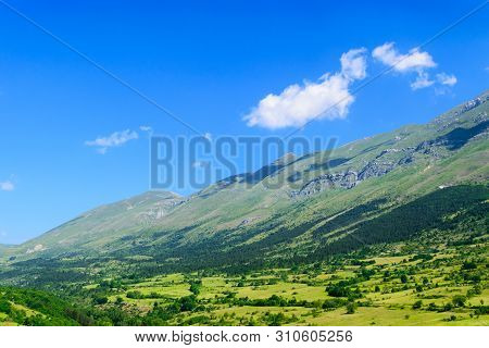 Landscape Of Apennines Mountains In The Background Of Blue Summer Sky And Clouds Casting The Shadows
