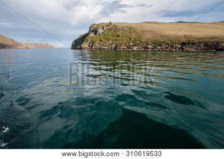 Turquoise Water Of Lake Baikal With A Rock. Taken From The Ship. There Is A Strait Between The Rocks