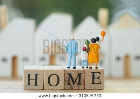 Miniature People: Family Stand On Wood Block Words Home And Looking To Home. Concept Of Plan For The