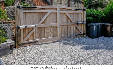 Tall Large Wooden Entry Electric Gates Which Are Closed.  Looking From The Inside With A Stone Drive