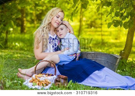 Portrait Of Loving Caucasian Mother With Her Little Kid. Posing With Basket Full Of Bread Rings Outd