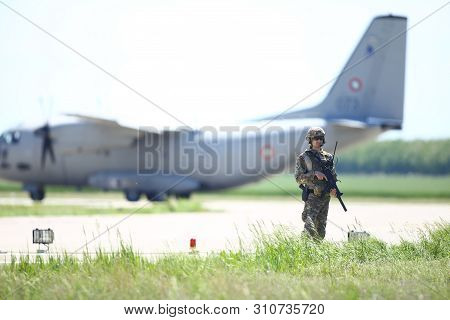 Boboc, Romania - May 22, 2019: Romanian Army Soldier Patrols A Military Air Base, With An Alenia C-2