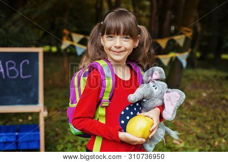 Little Girl With A Backpack, An Apple And An Elephant. Back To School. The Concept Of Education, Sch