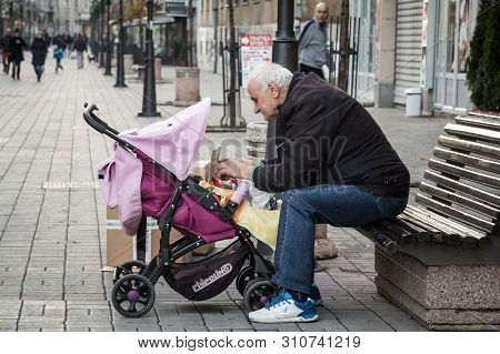 Smederevo, Serbia - December 20, 2014: Old Man, A Grandfather, Taking Care As A Grandparent Of His G
