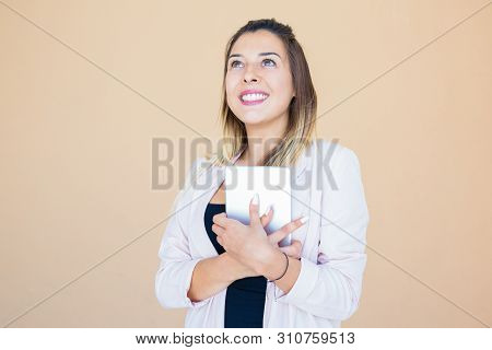 Happy Joyful Tablet User Thanking God. Young Woman In White Jacket Embracing Mobile Pc, Looking Up A