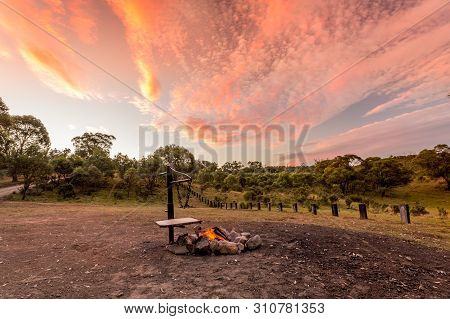Campfire With Fire Burning In A Campground In The Australian Outback And A Beautiful Sunset Sky Over