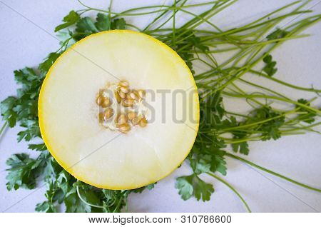 Open Halff Of Galia Melon Over Fresh Green Parsley Background. Overhead Shot