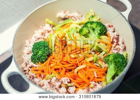 Brown Rice With Organic Unmixed Peeled Sliced Vegetables Cooking In Cast Iron Saucepan. Bright Brocc