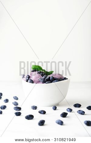 Ice-cream Decorated With Fresh Berries Of A Honeysuckle And Green Leaves On White Background. Close-