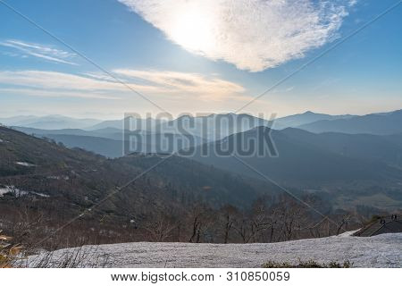 Panoramic View Of Beautiful Mountain Landscape, Snowy Mountain Peaks Covered By Forest With A Dark B