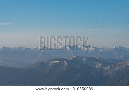 Panoramic View Of Beautiful Mountain Landscape, Snowy Mountain Peaks Covered By Forest With A Dark B