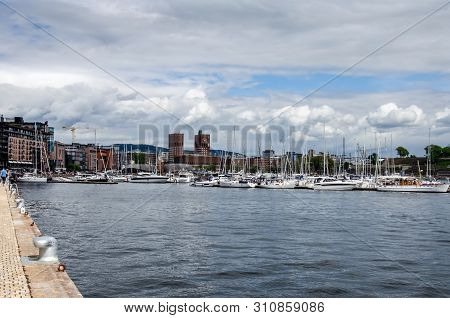 Oslo Cityhall And Aker Bridge. View From The Waterfront. Cityscape With Modern Architecture And Quay