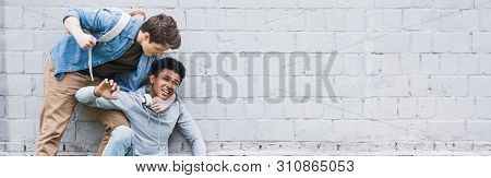 Panoramic Shot Of Aggressive Boy In Shirt Bulling, Going To Punch African American Boy In Hoodie