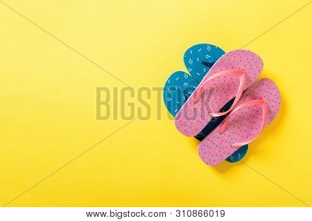 A Lot Of Colored Flip Flops On Yellowbackground. Top View With Copy Space