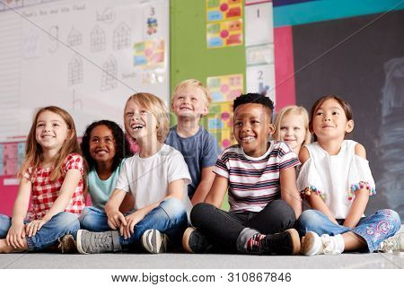 Group Of Elementary School Pupils Sitting On Floor In Classroom