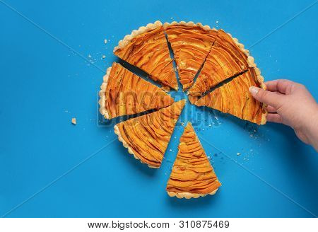 Homemade Sweet Potato Tart, In Flower Shape, Cut In Slices And A Woman Hand Grabbing A Piece Of The 