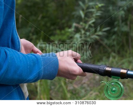 Man Holds Fishing Rod Close Up