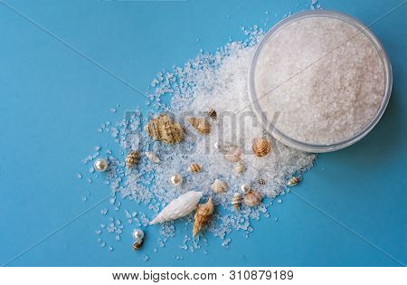 Sea Salt For Exfoliation On Blue Background With Sea Shells, Sea Salt Mineral Grains In Round Jar.