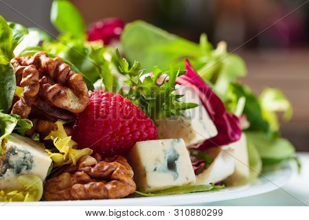 Green Salad With Slices Of Blue Cheese , Raspberries And Walnuts.