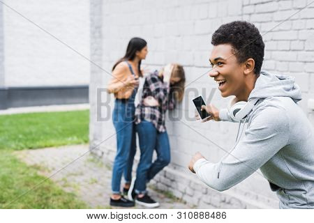 Selective Focus Of Smiling African American Boy Shooting Bulling Of Scared Teenager