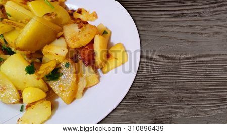 Baked Fried Golden Potatoes With Garlic And Parsley In White Plate On Dark Vintage Wooden Grunge Tab