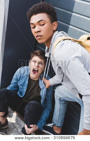 Selective Focus Of African American Boy In Hoodie And Jeans Bulling Screaming And Scared Boy